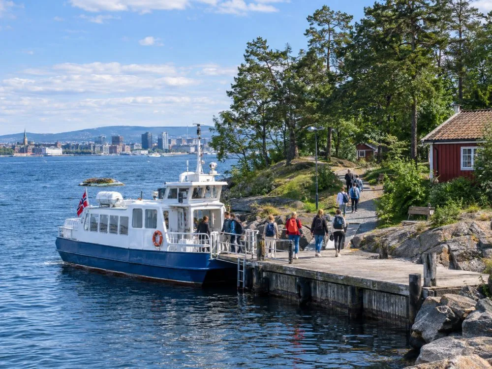 A Ruter island boat alongside the little quay at Hovedøya, with passengers stepping ashore onto the wooded island a short crossing from the centre of Oslo.